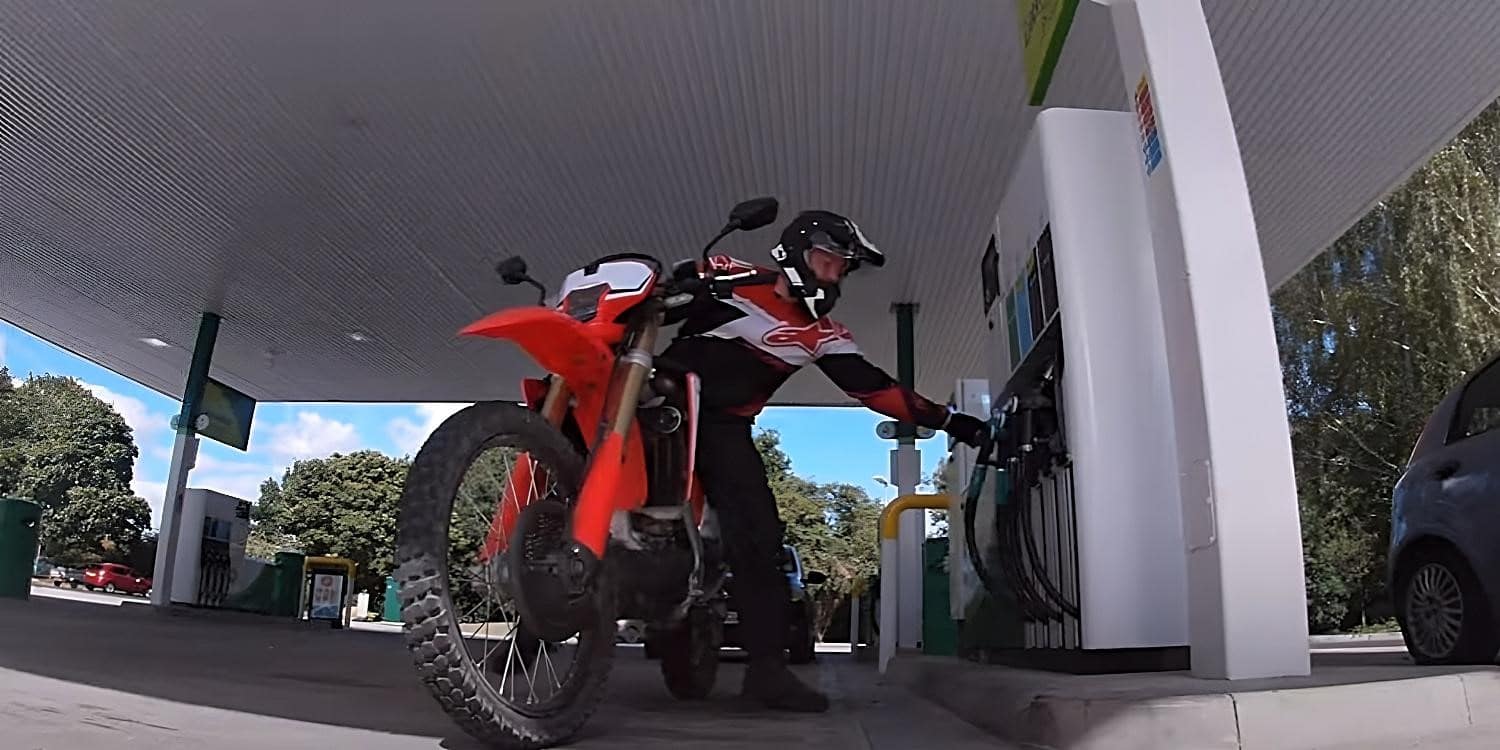 A rider reaching for or restoring the hose at a gas station while still seated on the bike along the Pacific Coast Highway, a breathtaking coastal route that winds along the Pacific Ocean for more than 470 miles between Los Angeles and San Francisco, offering spectacular scenery of towering cliffs and jagged mountains falling into the surf. The road goes by many names as it was built piecemeal and cuts across several jurisdictions. The Southern California PCH called State Route 1 (SR 1) is unmatched due to its abundance of sweeping meanders and generous switchbacks, breathtaking viewpoint locations, restaurants, lodging options, and biker-friendly fuel stops. In case you have to refuel, alight from the bike to avoid dousing yourself with gas and to make a run for it in case you need to.