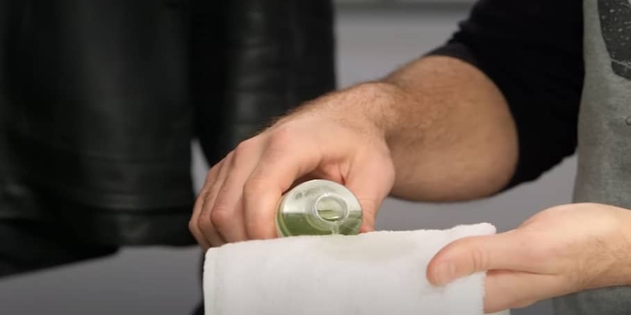 Dispensing a small quantity of cleaning liquid onto a white microfiber cloth.