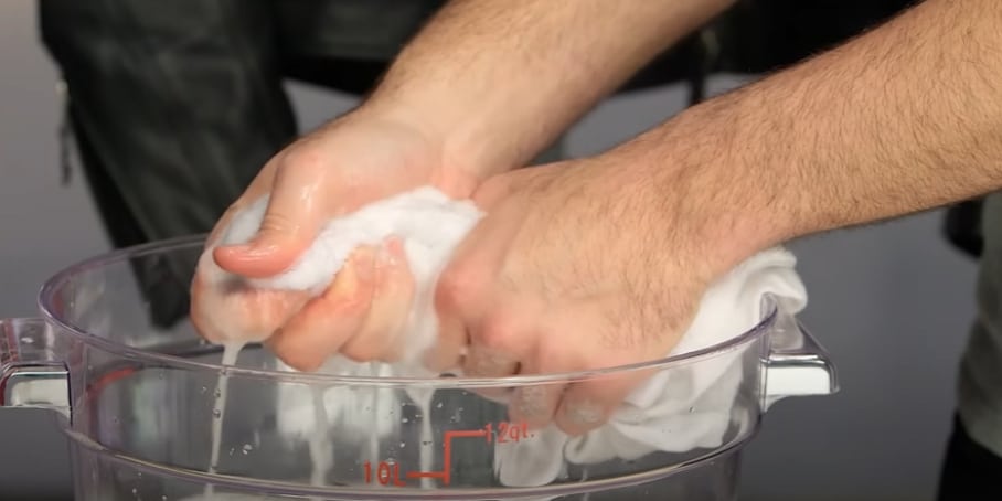 Rinsing the microfiber cloth in warm water, not hot, to eliminate dirt and grime before reusing it for cleaning.