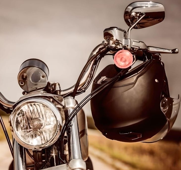 The Shoei J Cruise helmet hangs from a bolt-mounted Lidlox™ helmet lock on a Yamaha SR400 cafe racer with “aped” handlebars.