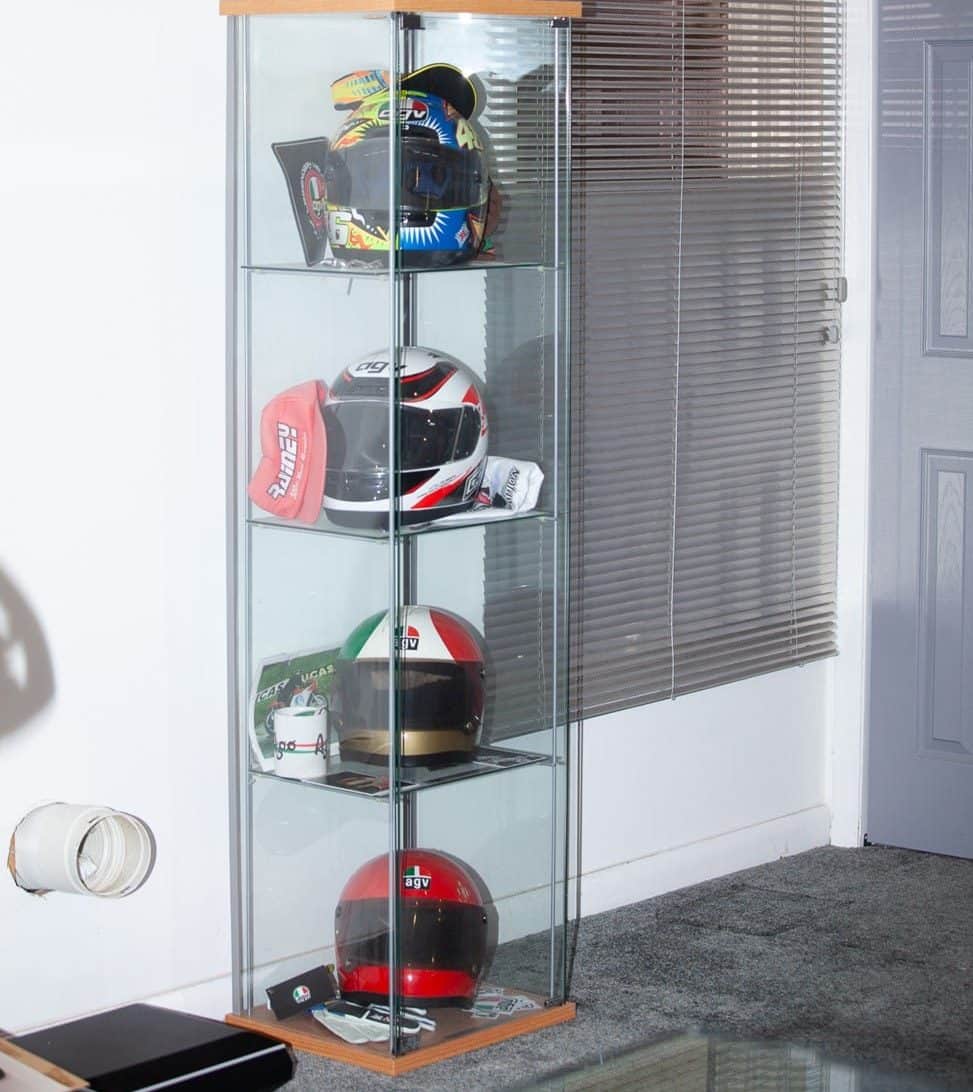 From the bottom up, one of my helmet collections in my Maryland office showcases Niki Lauda's AGV X1, Giacomo Agostini's AGV X3000, Wayne Rainey's AGV Quasar, and Valentino Rossi's AGV Pista GP R. Positioned at the top are AGVSPORT’s motorcycle riding boots.