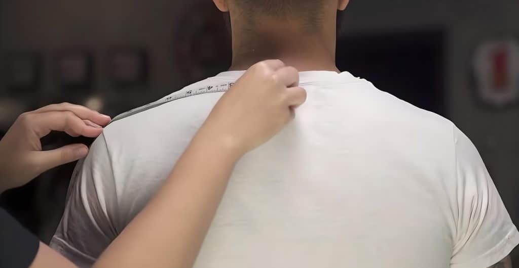 Taking body length measurements to refer to it in sizing charts, made easier with the help of a friend. You can have someone measure three times for each reading and average.