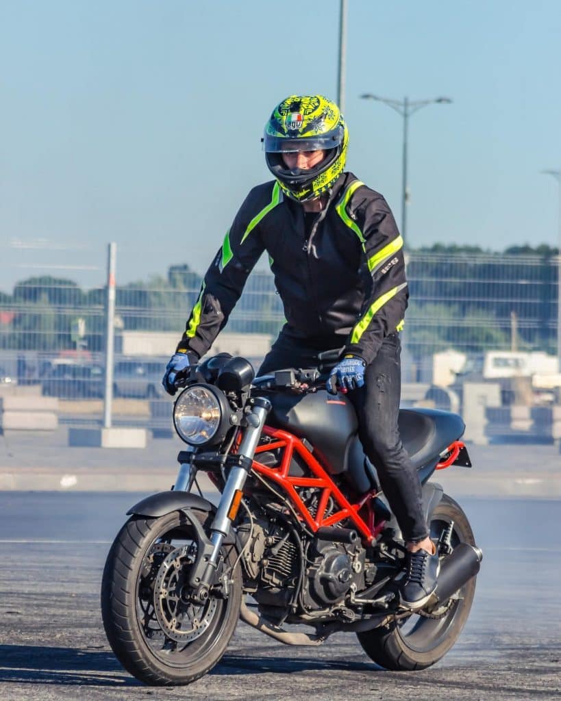 Preparing to perform a daring stunt: standing on the motorcycle in readiness.