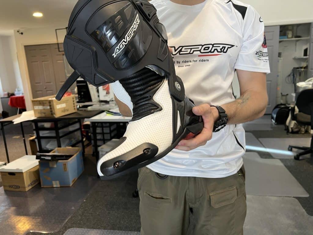 Do You Need Tall Motorcycle Boots? Explore the Pros and Cons Denis displays the AGVSPORT Monza race boot, showcasing ventilation perforations in the white section, protective toe sliders on the front-right, and armored heel plates at the back for enhanced safety and breathability.