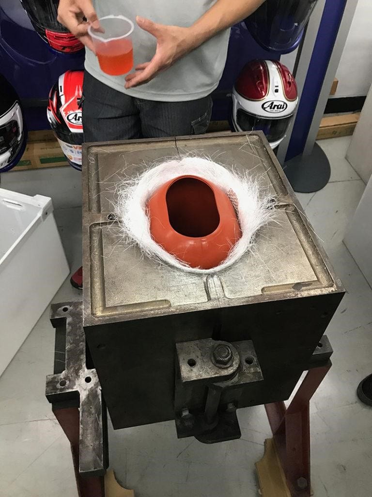 Next, resin is poured into the mold. Inside the mold, a robust rubber bag, resembling a water bottle in shape (thus termed “bag molding”), is carefully positioned. The mold's top is secured, and the bag is inflated, exerting pressure to compress the resin and fiberglass layers into a thin, integrated shell.