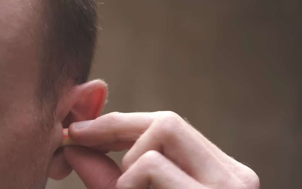 Inserting soft foam earplugs before putting on gloves