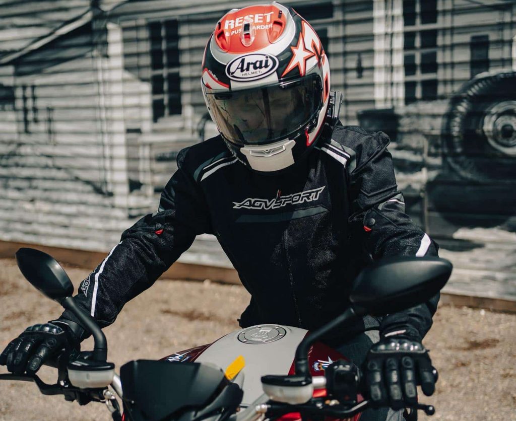 In the Arai Corsair-X Nicky Reset Helmet, the top vents are displayed in different states of closure, arranged from left to right: Open, Closed, and Half Closed. The central vent features a port that directs airflow directly to the top of the head, providing noticeable ventilation. However, the other two vents, located on either side of the central one, direct airflow into the interior above the liner, resulting in a less direct sensation of airflow.