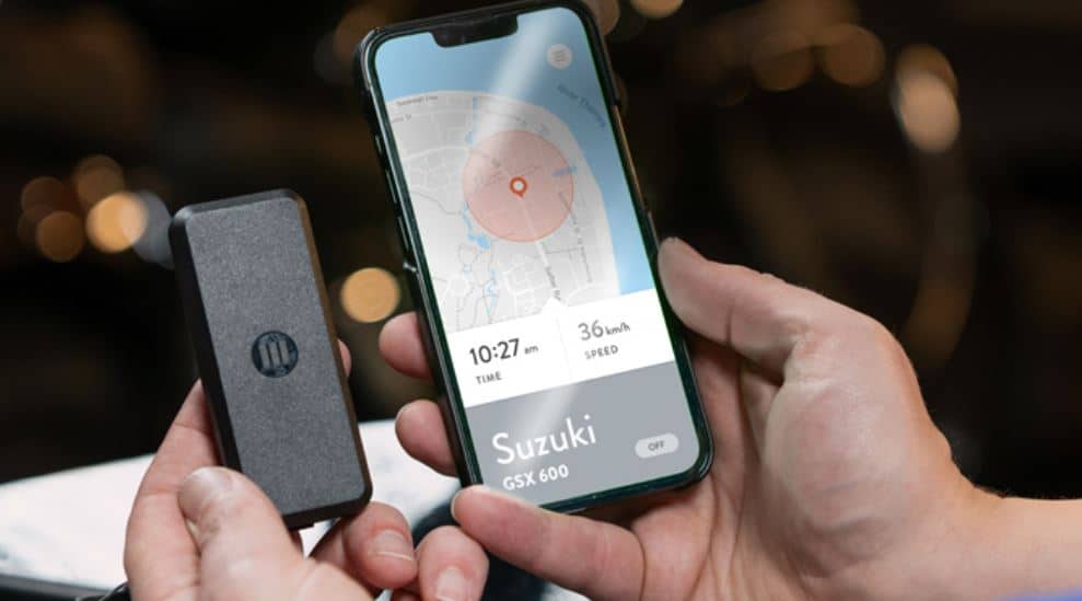 Testing the Monimoto tracker app on my smartphone to locate my Suzuki GSX600 motorcycle. In my left hand, I hold the exact model M7 tracker device, which I have successfully installed on the bike