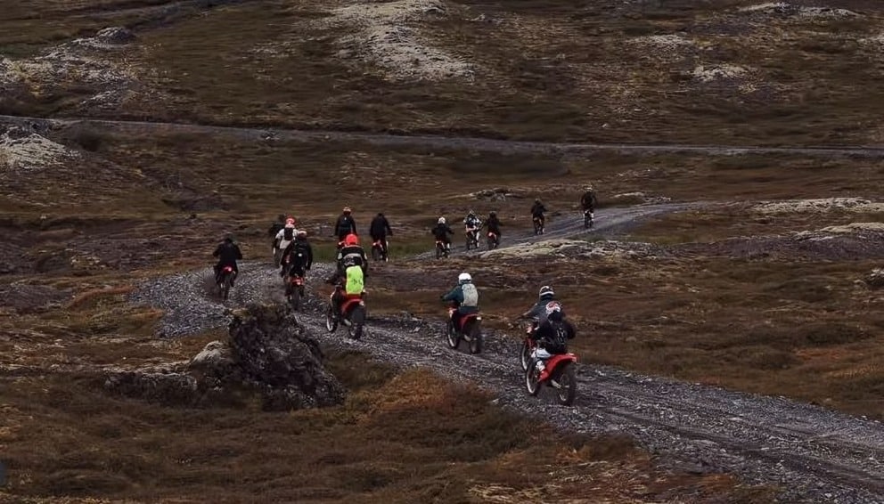 Group of adventure riders on off road motorcycles following a local guide through dirt trails and mountain roads in Vietnam