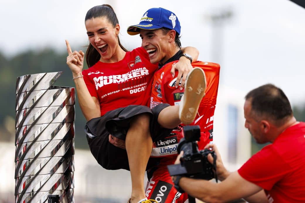 Marc Márquez and his partner celebrate his MotoGP victory together on the podium, sharing a joyful moment following his 7th MotoGP title win.