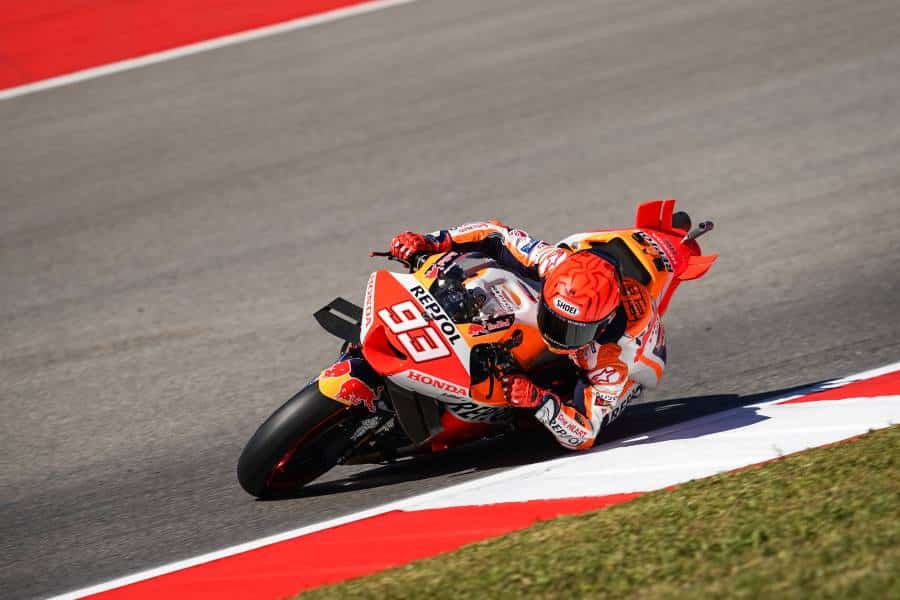 Marc Márquez riding the Repsol Honda #93 through a tight corner during a MotoGP race, showcasing the iconic orange-white Repsol Honda livery in full action.