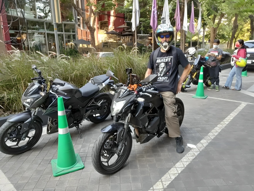 Taking a stretch on my Kawasaki Z250SL in Thailand after 45 minutes of riding to prevent muscle stiffness, improve blood flow, and reduce the risk of motorcycle back pain.