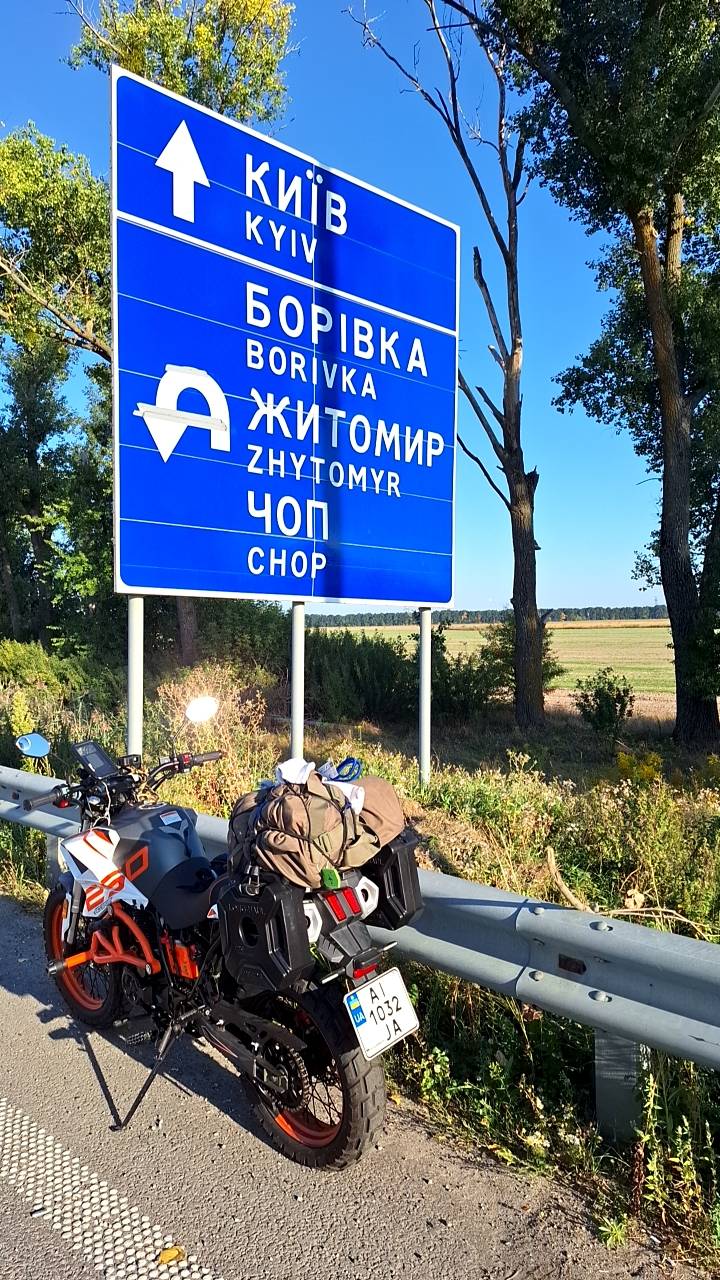 My adventure motorcycle Tekken 250 during a long-distance off-road ride in Ukraine, parked by a highway sign near Kyiv and fully loaded with luggage. That setup taught me firsthand how much luggage balance affects posture.