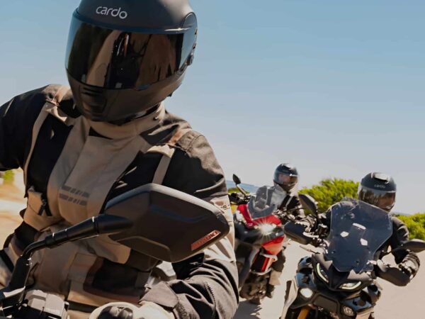 Three riders wearing Cardo BEYOND GT and GTS helmets showing integrated mesh intercom modules, 53 mm speakers, and aerodynamic shell design.
