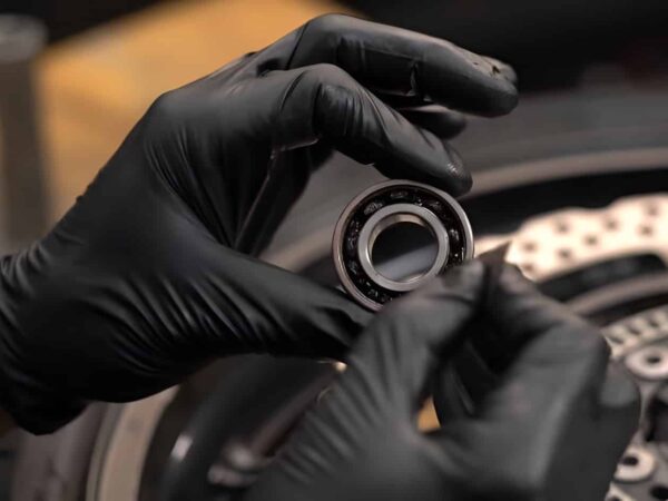 Inspecting a new motorcycle wheel bearing before installation. Checking for smooth rotation and verifying the bearing number to ensure the correct fit for the wheel hub.